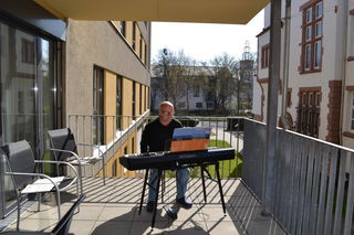 Der Koordinator und Künstler Stephan Herget bei einem seiner Auftritte auf dem Balkon des Stadtteilzentrums an der Kinzig in Hanau. Besonders begeistert waren die Bewohner von den Melodien von Haydn, Beethoven und anderen.