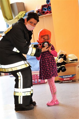 Brandschutzerzieherin Melanie Haas und eine junge Dame mit Fluchthaube