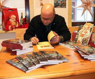 Illustrator Christopher Tauber signiert einige der Comics, die ab sofort in der Tourist-Info zum Verkauf stehen.