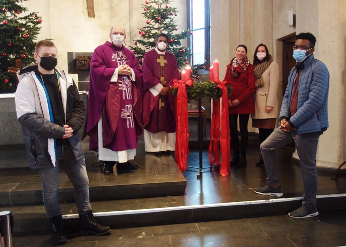 Mit Abstand  und mit Mund-Nasenschutz das Gespräch mit jungen Leuten gesucht: Pfarrer James  (dritter von links am Adventskranz in Mariae Namen