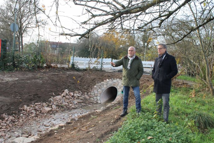 Wo am Wendehammer Zur Breulwiese die innerörtliche Entwässerung in den neuen Graben mündet: Stadtrat Thomas Morlock (rechts) lässt sich von HIS-Abteilungsleiter Ruess die Zusammenhänge erläutern. 