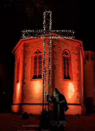 Das Foto zeigt den Nikolaus vor der schön beleuchteten Friedenskirche in Brachttal-Schlierbach.