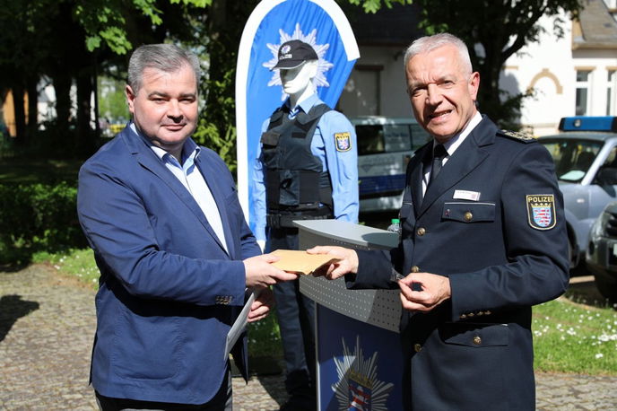 Bei der Verabschiedung des Hilfskonvois übergibt HPT-Präsident Karl-Heinz Reinstädt (r.) im Auftrag des Hessischen Innenministers Peter Beuth Schutzschleifen in den ukrainischen Landesfarben an den ukrainischen Generalkonsul in Frankfurt.