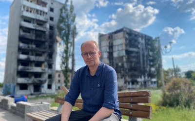 Michael Brand vor den zerstörten Wohnhäusern in dem befreiten Gebiet von Borodjanka.
